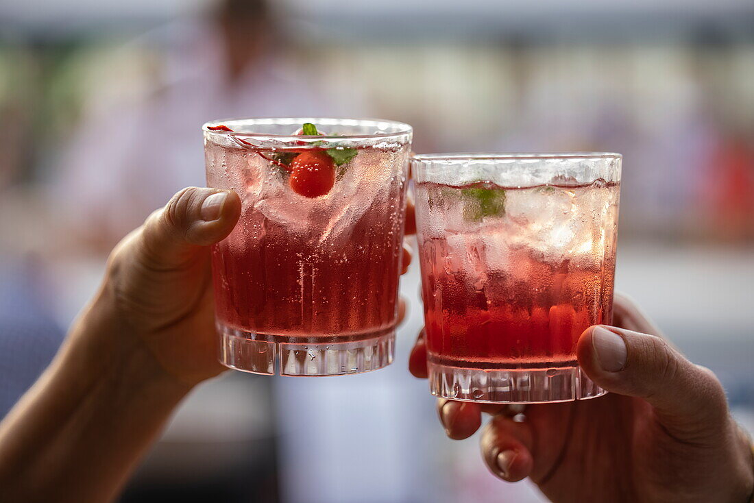 Zwei Hände mit Cocktails während einer Party auf dem Pooldeck an Bord von Kreuzfahrtschiff Vasco da Gama (nicko cruises), in der Nähe der Philippinen, Südostasien