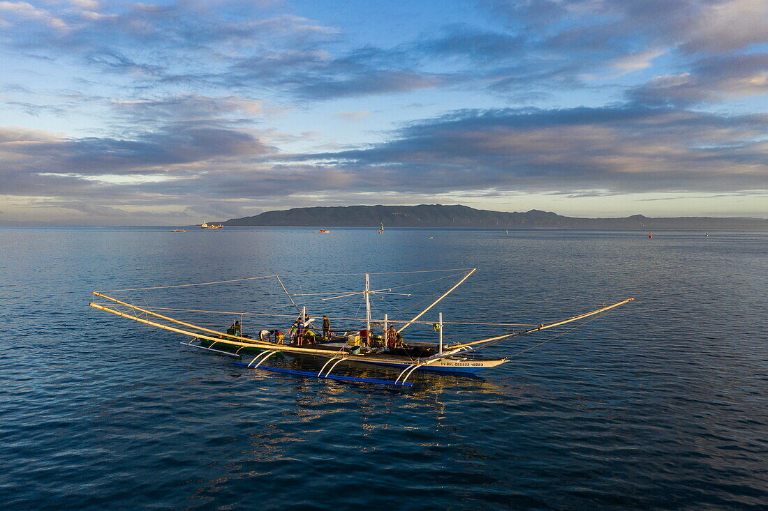  Aerial view of a traditional Bangka outrigger canoe fishing boat with coast in the distance, Tagbilaran, Bohol, Philippines 