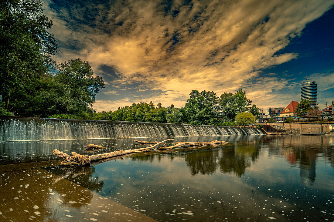 Das Saalewehr im Paradies Park von Jena mit dem Jentower im Hintergrund bei Sonnenuntergang im Sommer, Jena, Thüringen, Deutschland