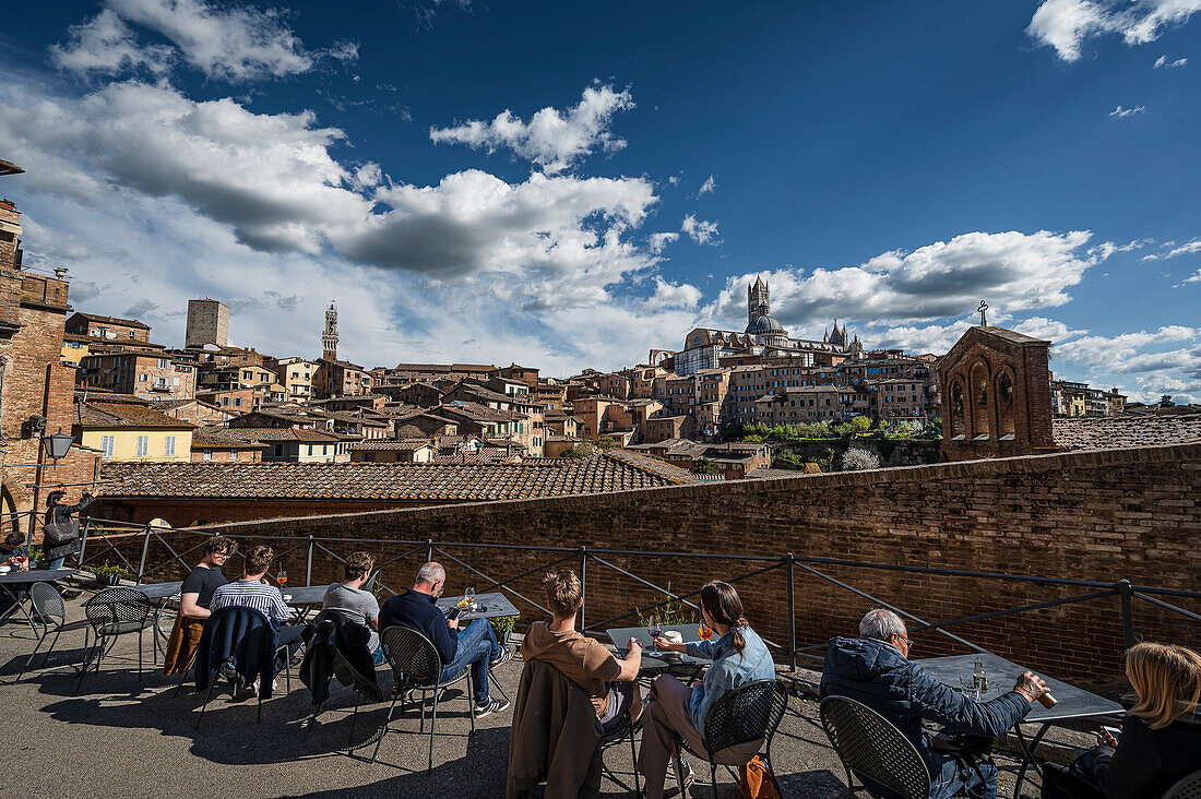  People with drinks in restaurant/cafe, in the foreground, view of old town cathedral with tower, Siena, Tuscany region, Italy, Europe 