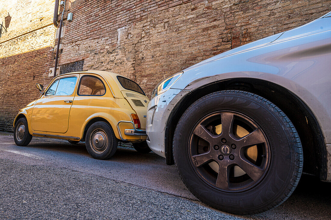  small Fiat 500 stands next to large SUV car, Siena, Tuscany region, Italy, Europe 