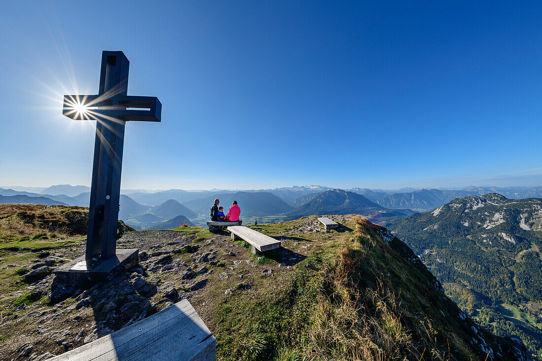  Three people hiking sitting at the summit cross of the Loser, Loser, Totes Gebirge, Salzkammergut, Styria, Austria 