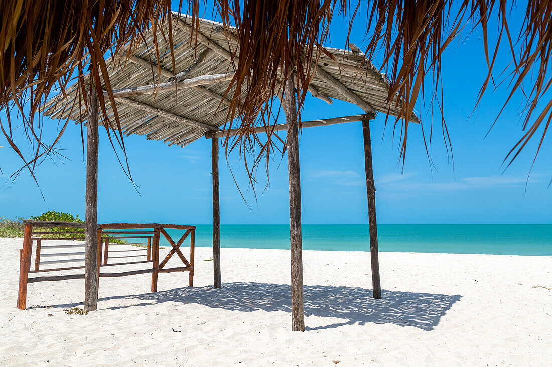 Strohgedeckte Palapa-Gebäude am Sandstrand mit blauem, ruhigem Meer, Küste am Golf von Mexiko, Celestun, Yucatan, Mexiko