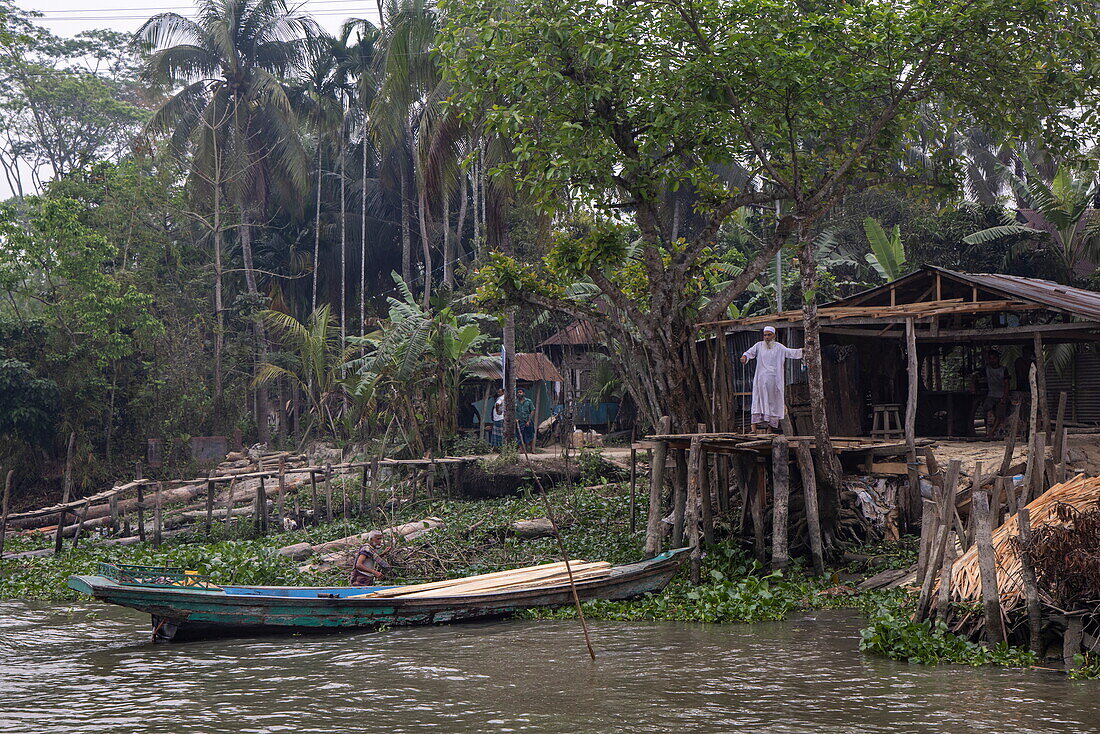 Kanu, üppige Vegetation und ein Mann am Fluss Belua, Boithakata, Distrikt Pirojpur, Bangladesch, Asien