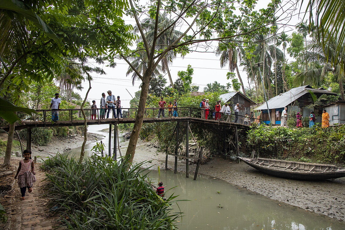  Passengers of river cruise ship RV Thurgau Ganga Vilas (Thurgau Travel) and children crossing footbridge in Kumar Pada village (potters&#39; colony), Kaukhali (Kawkhali), Pirojpur District, Bangladesh, Asia 