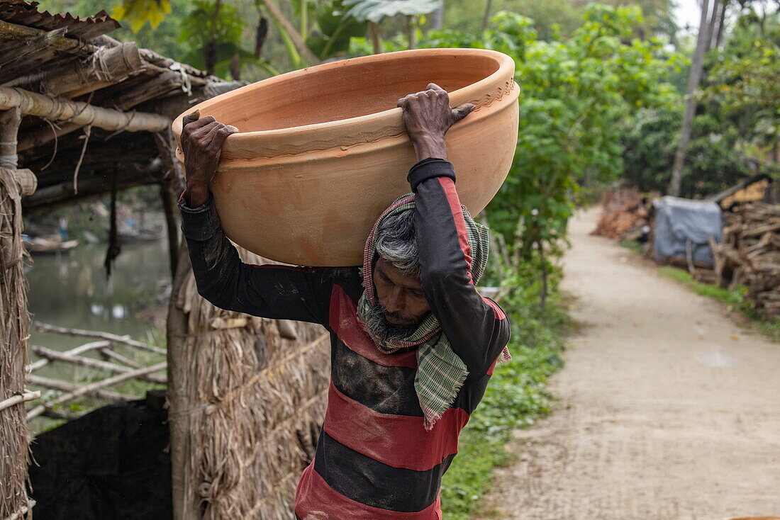 Mann trägt riesigen Keramiktopf in der Töpferkolonie Kumar Pada, Kaukhali (Kawkhali), Distrikt Pirojpur, Bangladesch, Asien