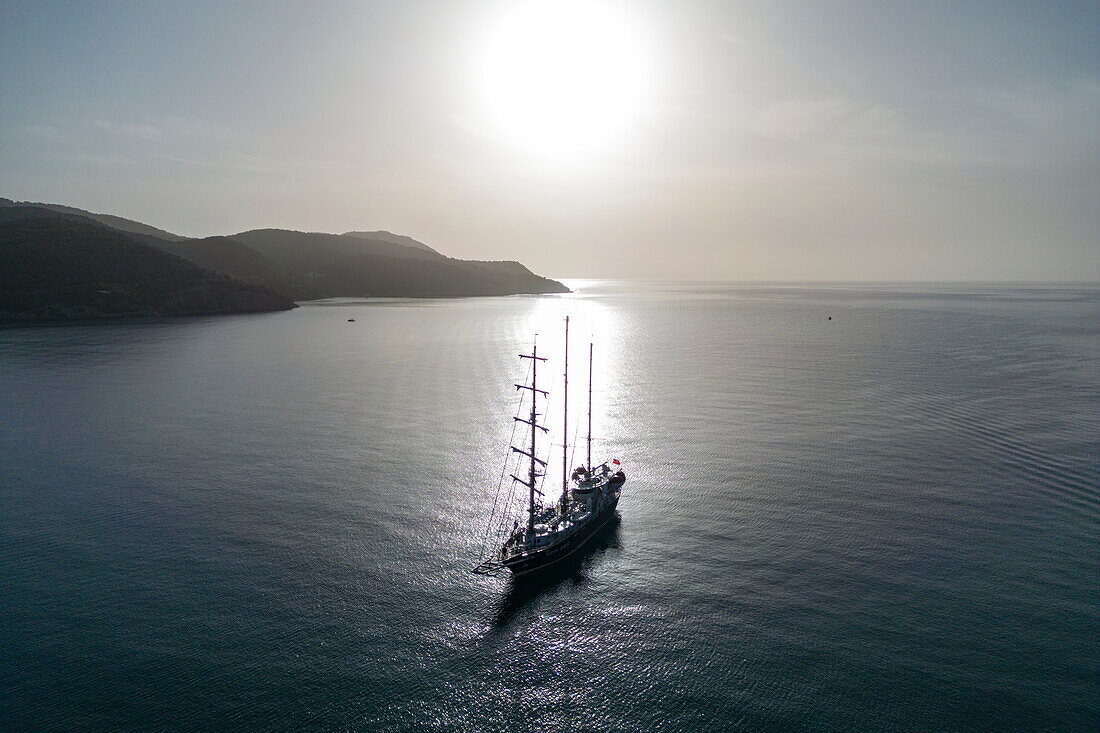  Aerial view silhouette of sailing cruise ship Running on Waves (M&#39;Ocean) anchored in bay at sunrise, Poros, Attica, Greece, Europe 