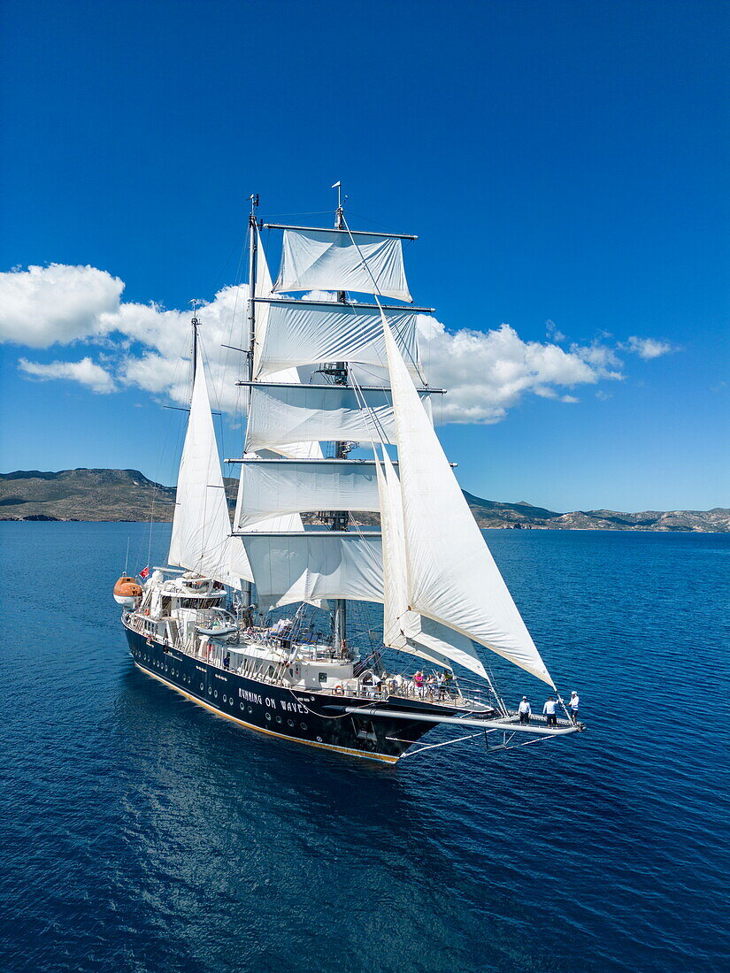 Luftaufnahme des dreimastigen Segelkreuzfahrtschiffs Running on Waves (M'Ocean) unter Segeln, Adamas, Milos, Südliche Ägäis, Kykladen, Griechenland, Europa