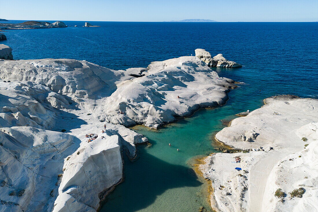  Aerial view of people at Sarakiniko beach with its grey-white volcanic rock with bay and coastline, Sarakiniko, Milos, South Aegean, Greece, Europe 