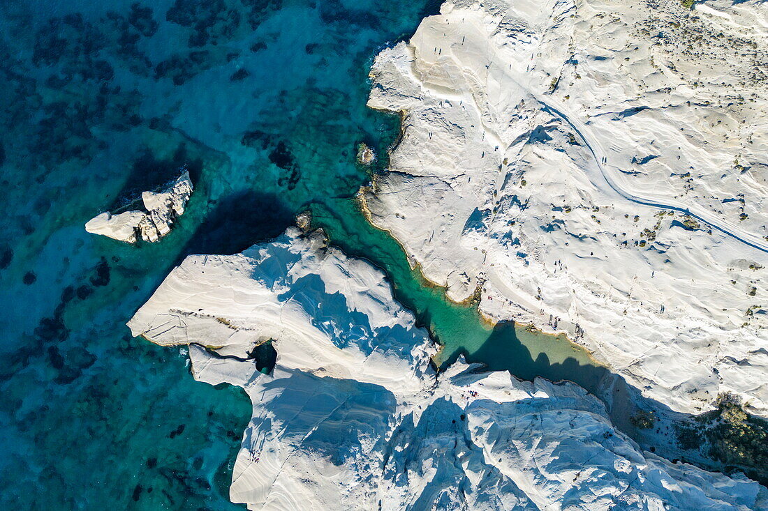  Aerial view of people at Sarakiniko beach with its grey-white volcanic rock with bay and coastline, Sarakiniko, Milos, South Aegean, Greece, Europe 