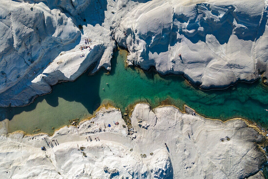  Aerial view of people at Sarakiniko beach with its grey-white volcanic rock with bay and coastline, Sarakiniko, Milos, South Aegean, Greece, Europe 