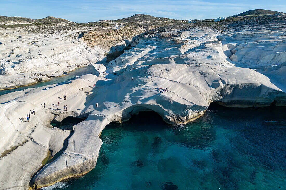  Aerial view of people at Sarakiniko beach with its grey-white volcanic rock with bay and coastline, Sarakiniko, Milos, South Aegean, Greece, Europe 