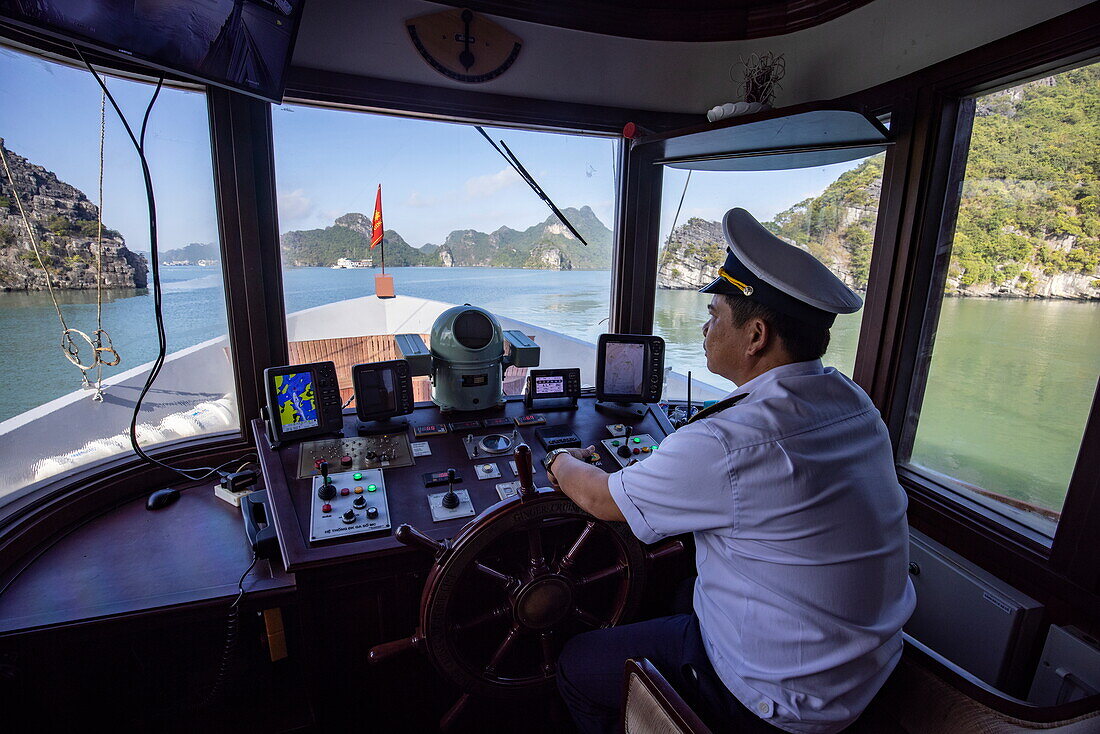 Kapitän auf der Brücke des Kreuzfahrtschiffs Ginger (Heritage Line) und Karstinseln, Lan Ha Bay, Haiphong, Vietnam, Asien