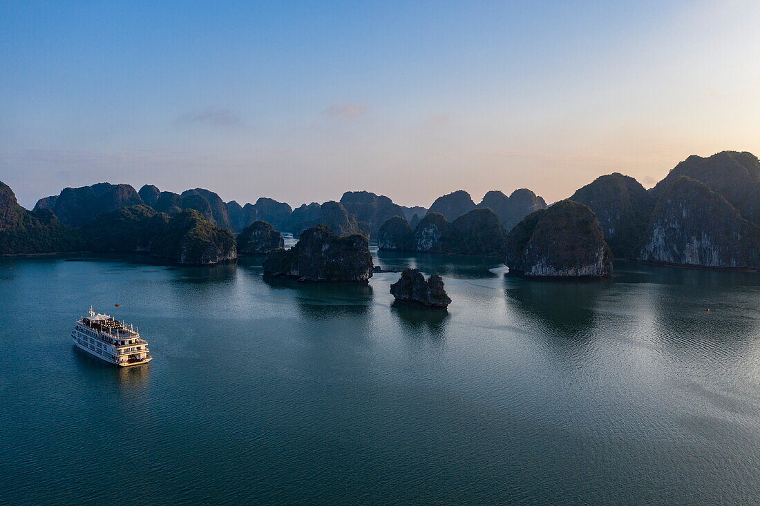 Luftaufnahme eines Ausflugsschiffs inmitten von Karstinseln bei Sonnenuntergang, Lan Ha Bay, Haiphong, Südchinesisches Meer, Vietnam, Asien