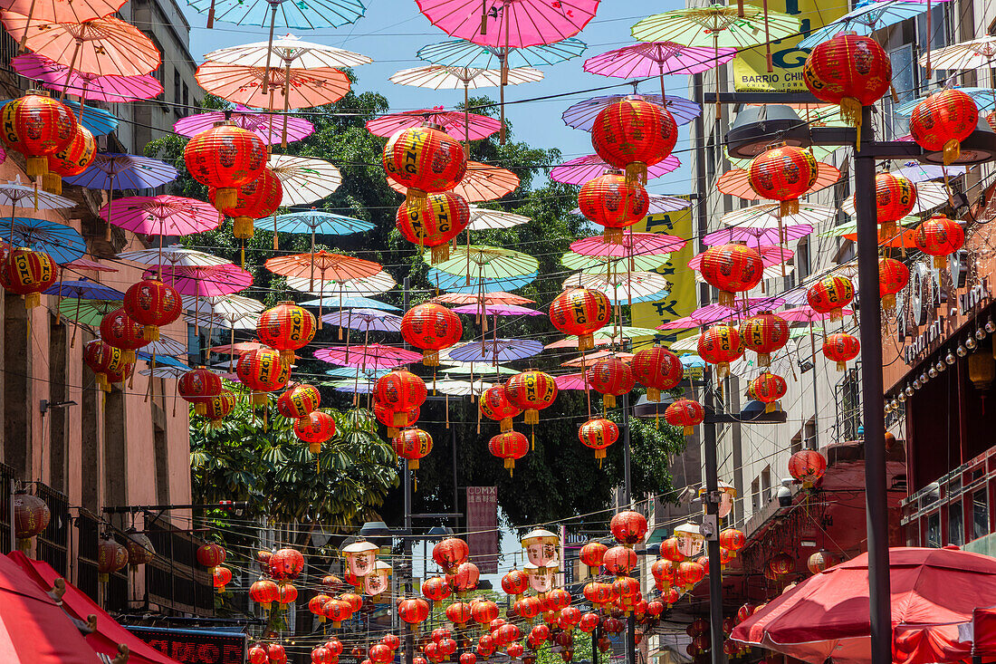 Red paper Chinese lanterns and umbrellas hanging above the street in Chinatown, Mexico City, Mexico advertising various restaurants