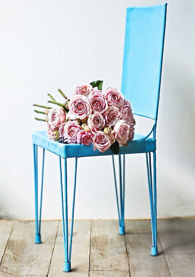 A bunch of pink roses on a blue chair