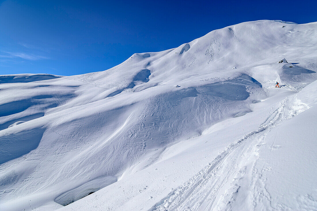  Woman on ski tour walks through wide snowy landscape, Schwebenkopf, Kelchsau, Kitzbühel Alps, Tyrol, Austria 