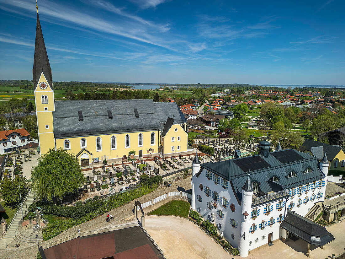 Frau fährt mit dem Rad durch Bernau mit Blick auf Kirche und Bonnschlössl, Bernau, Bodensee-Königssee-Radweg, Oberbayern, Bayern, Deutschland