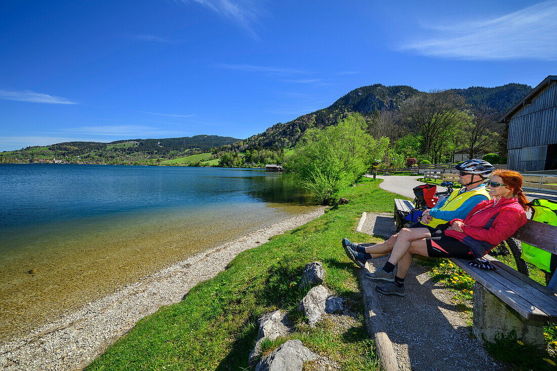  Man and woman on the Lake Constance-Königssee cycle path sitting at Schliersee and taking a break, Schliersee, Upper Bavaria, Bavaria, Germany 