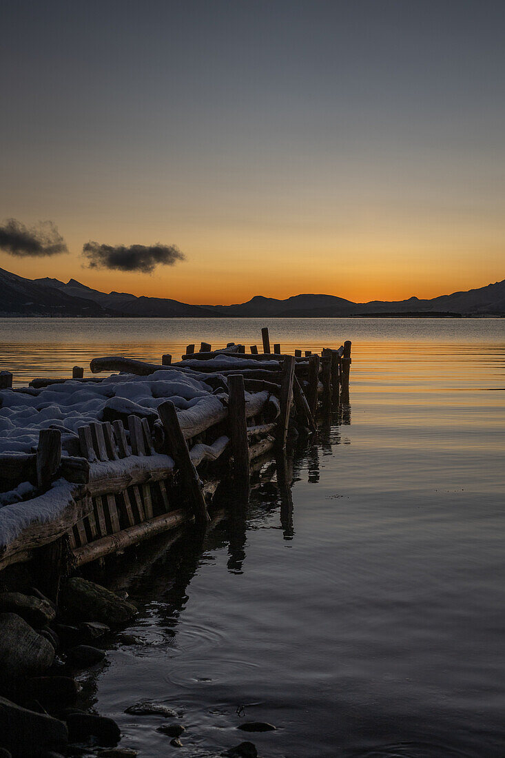 Winter in der Region Trömso, Kvaloysletta, Bucht mit altem Steg im Dämmerungslicht