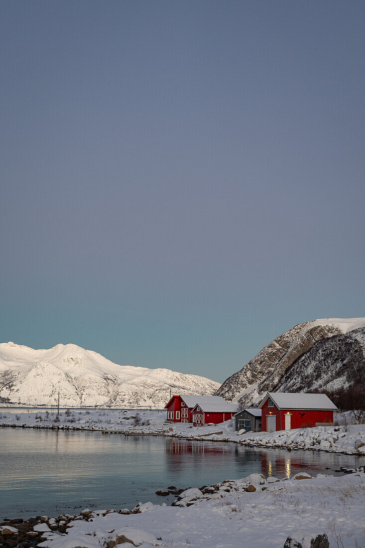  Winter in the Trömso region, Tromvik, typical traditional house with mountains in the twilight 