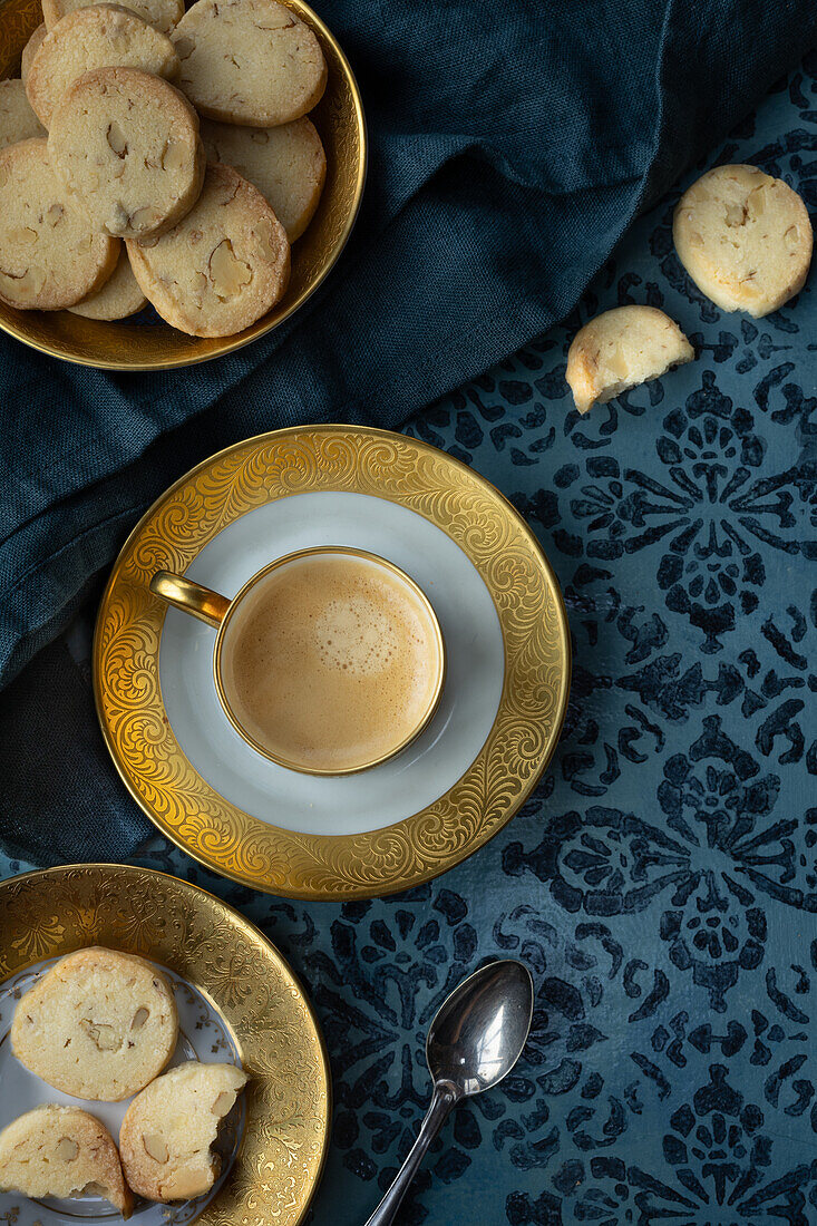 Sablés auf Teller mit Goldrand und Kaffee, mit blauem Untergrund