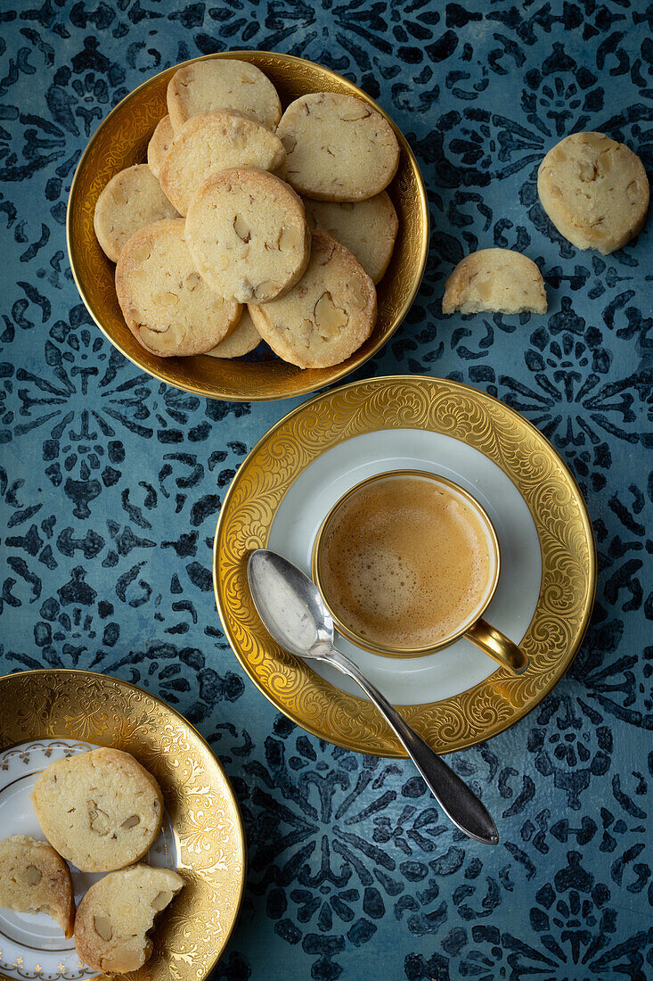 Sablés auf Teller mit Goldrand und Kaffee, mit blauem Untergrund 