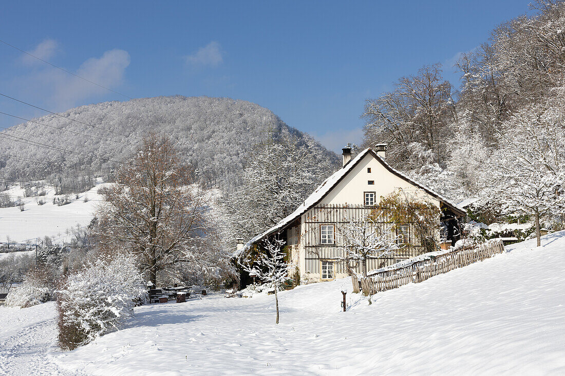  Traditional house in the Jura with snow, hills and blue sky. 