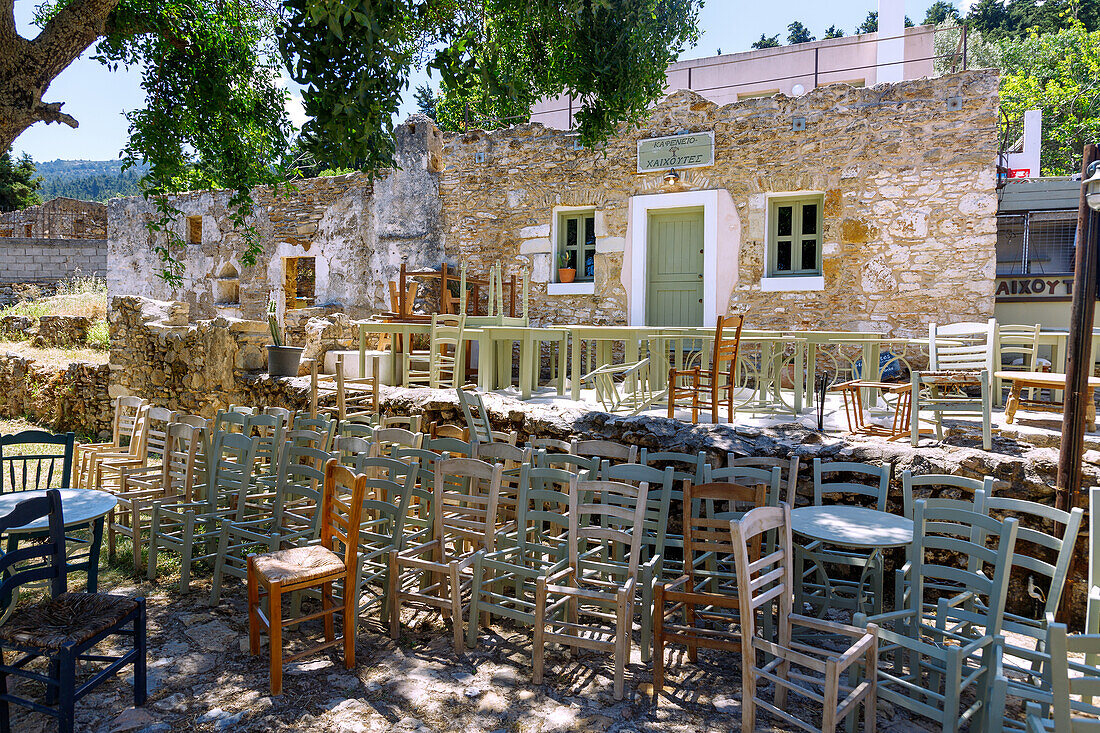 vor dem Kafenion in Agios Dimitrios aufgereihte und gestapelte Holzstühlle und Tische zur Vorbereitung der Saison-Eröffnung auf der Insel Kos in Griechenland