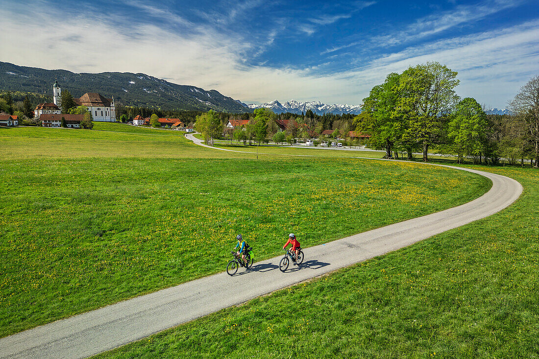  Man and woman cycling on the Lake Constance-Königssee cycle path with Wieskirche in the background, Wies, UNESCO World Heritage Wieskirche, Upper Bavaria, Bavaria, Germany 