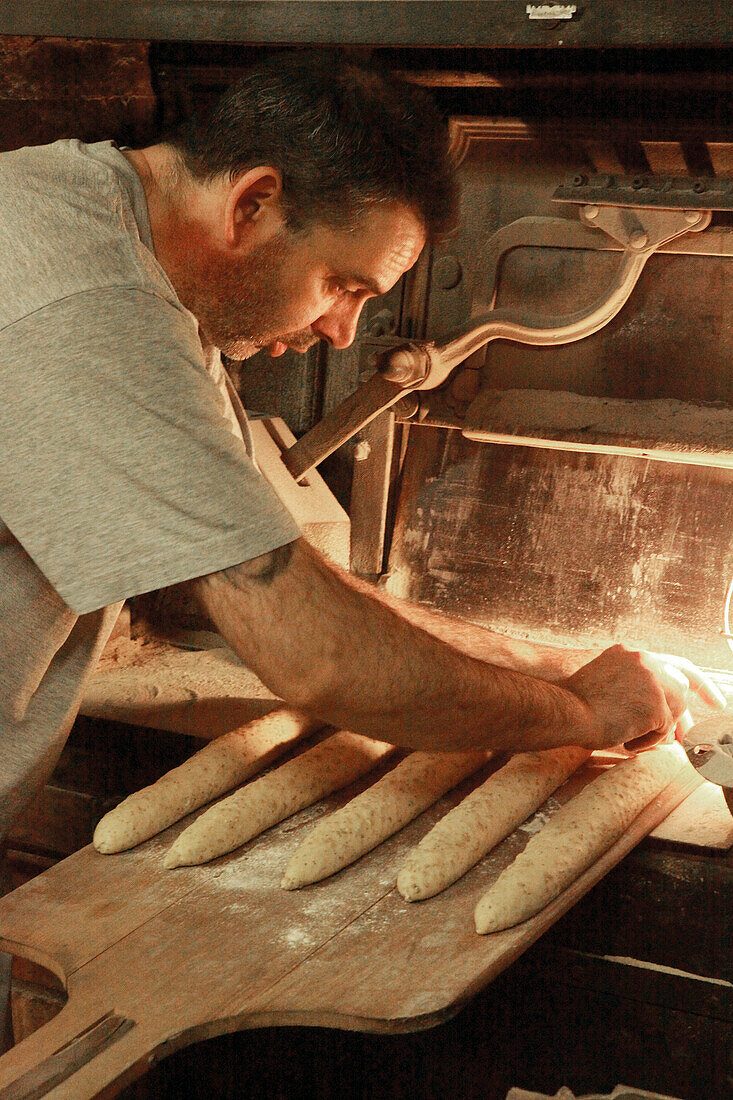  Baker puts baguettes in the oven 