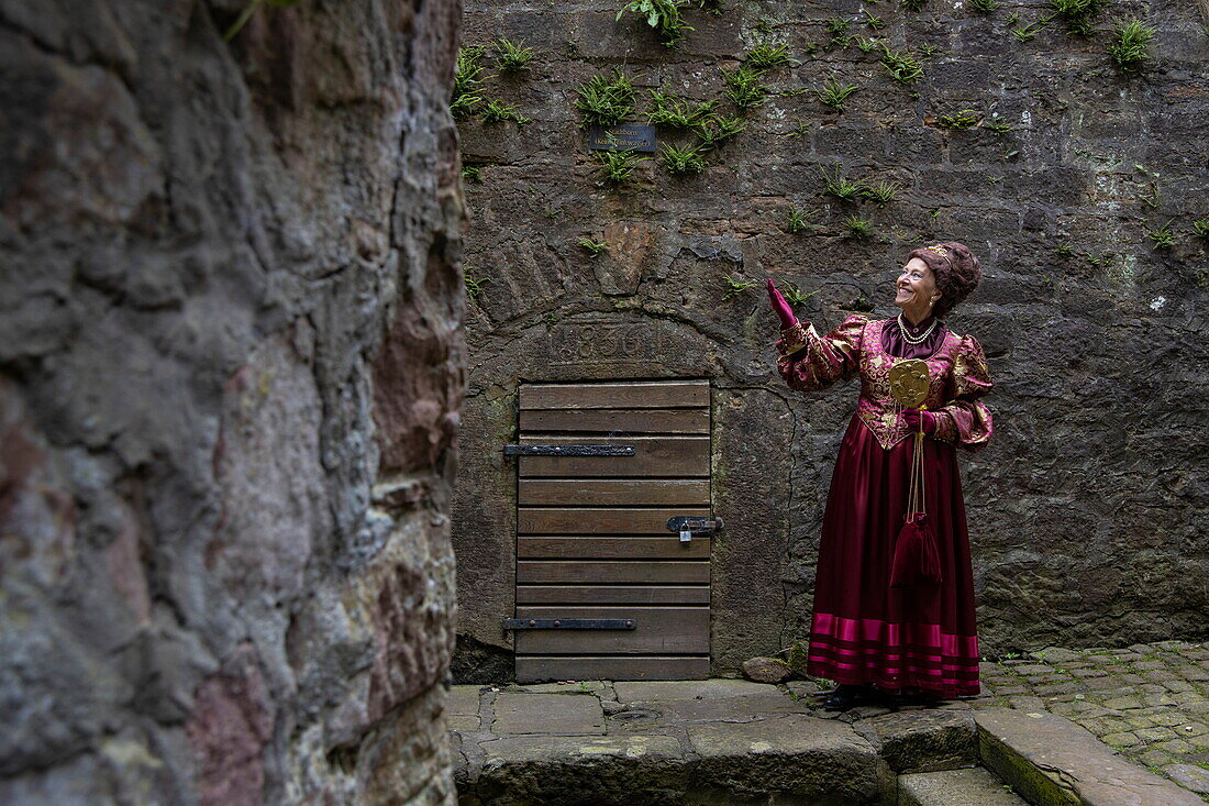 Frau im Kostüm der „Hofdame aus Kassel“, Figur aus dem Märchen der Brüder Grimm, erklärt historische Stadtmauer in der Altstadt, Steinau an der Straße, Spessart-Mainland, Hessen, Deutschland