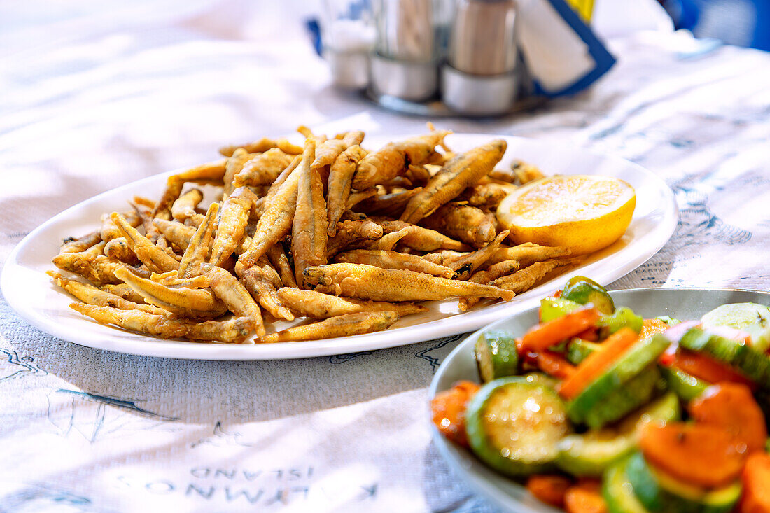 Panierte frittierte Sardinen (Gavros) mit Zitrone und Zucchini-Karotten-Gemüse, serviert in der Taverne in Emborió auf der Insel Kalymnos in Griechenland