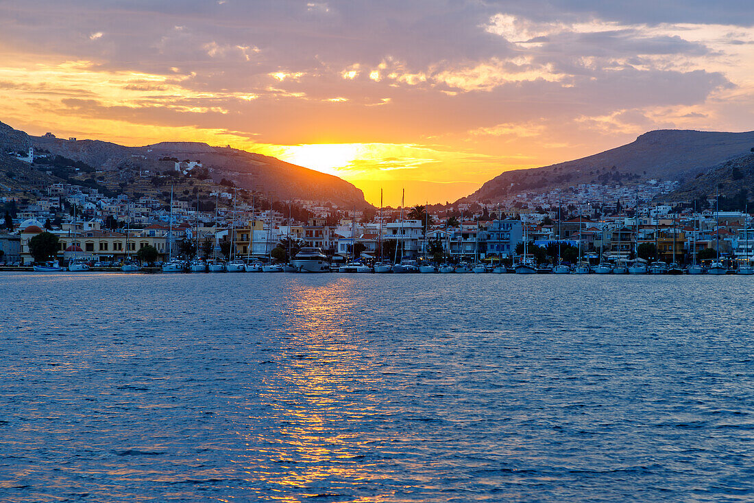 Sonnenuntergang hinter Póthia mit Rathaus (Dimarchio) und Booten im Hafen auf der Insel Kalymnos (Kalimnos) in Griechenland