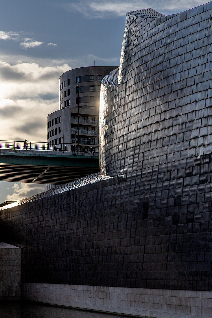  Jogger on bridge in front of Guggenheim Museum, Bilbao. Sun reflecting on facade. Basque Country, Spain 