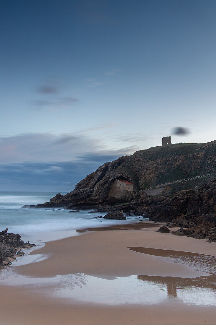  View over the beach to the rock chapel Ermita de Santa Justa. Blue sky. 