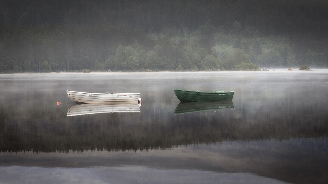 2 Ruderboote regungslos im See bei Nebel, Loch Morlich, Hochland, Highlands, Schottland, Großbritannien