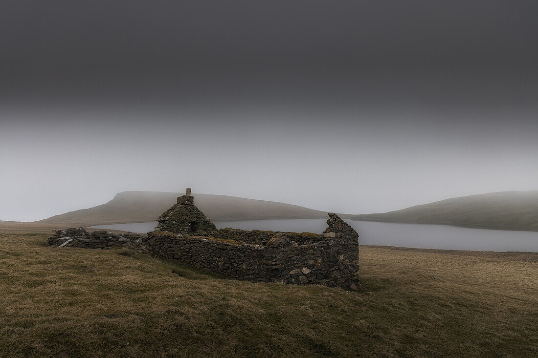 Verfallenes Cottage am See mit Regenwolken, Mainland, Orkney Islands, Schottland, Großbritannien