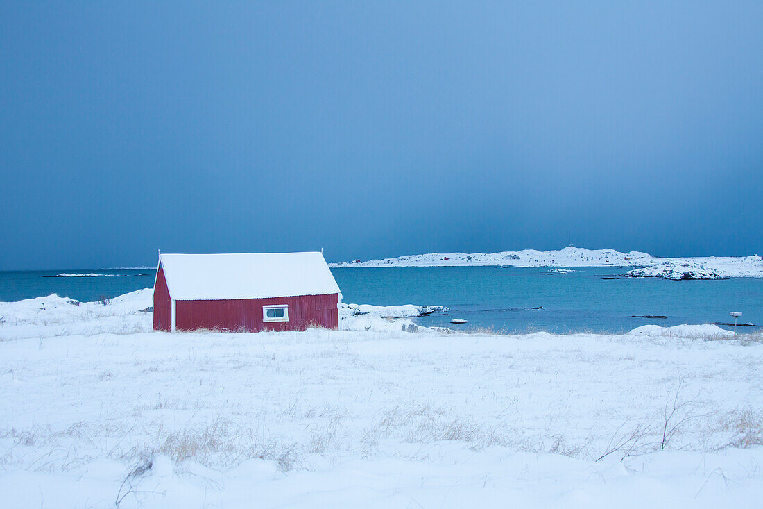 Hütte vor Schneewolken am verschneiten Fjord, Winter, Lofoten, Norwegen