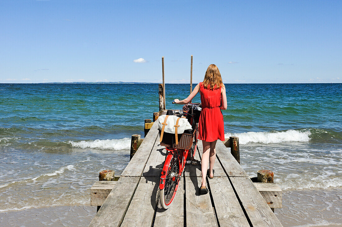 Frau mit einem Fahrrad auf einem Ponton am Strand von Moesgaard, Aarhus, Halbinsel Jütland, Dänemark, Nordeuropa