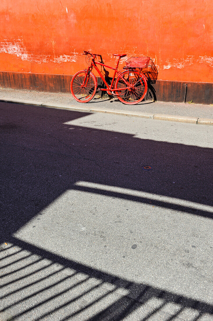 Red bike against a red wall in Graven street, Latin Quarter, Aarhus, Jutland Peninsula, Denmark, Northern Europe