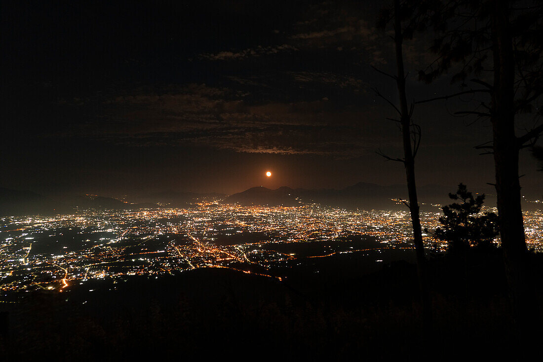 Blick auf den Golf von Neapel bei Nacht, mit Lichtern der Stadt, die die Küste erhellen und sich im ruhigen Wasser spiegeln, Kampanien, Italien, Europa