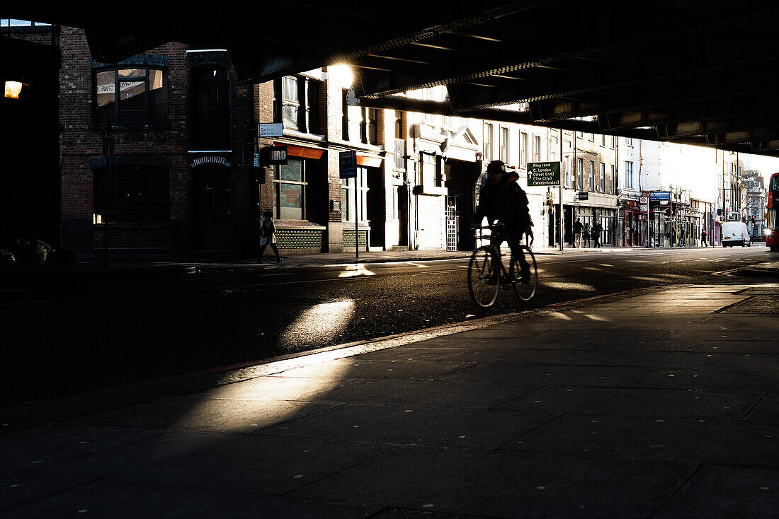 Radfahrer fährt unter einer Brücke in einer englischen Kleinstadt, England, Europa