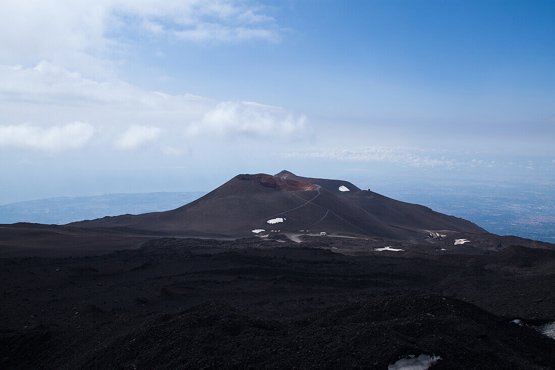 View of the summit of Mount Etna from the very top, featuring a blue sky.