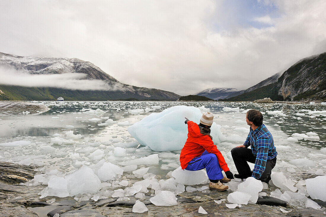 Couple sitting on ice, Pia Glacier,Cordillera Darwin,Beagle Channel (Northeast branch),Tierra del Fuego, Patagonia,Chile,South America