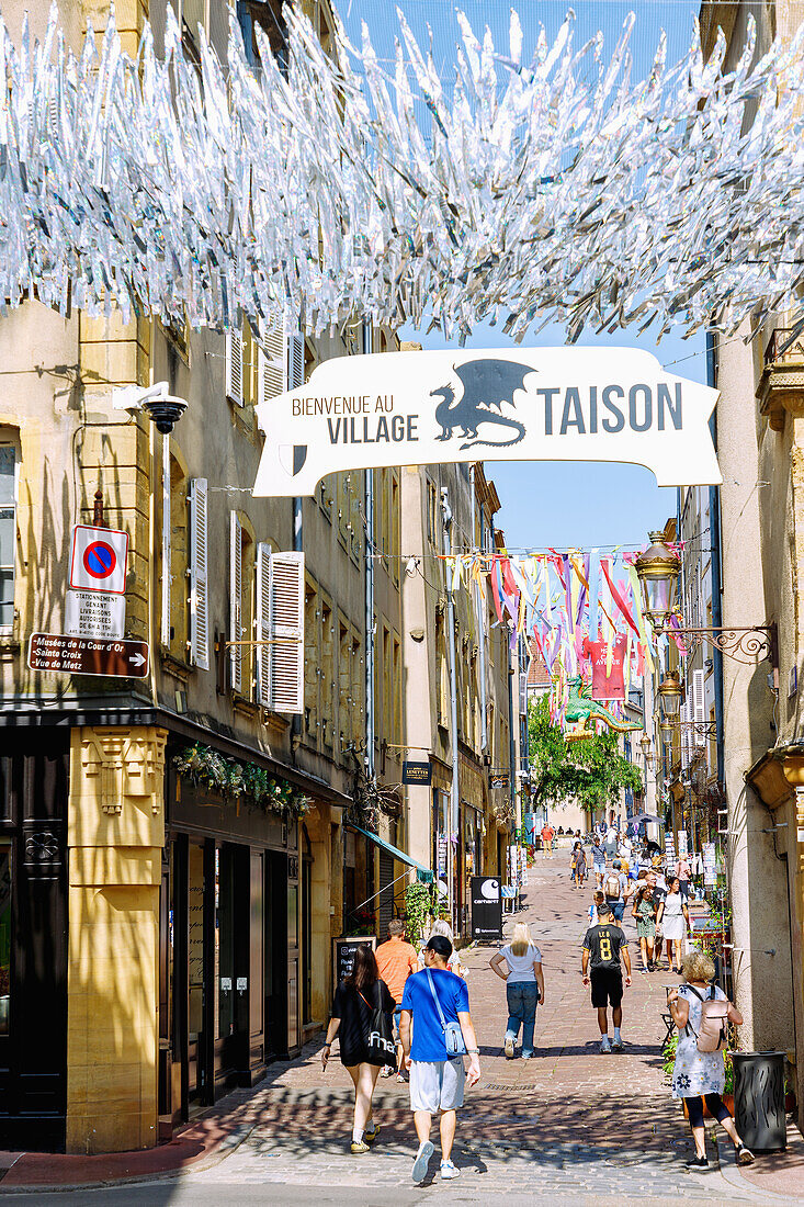  The old town street Rue Taison, decorated with colorful stripes and the legendary dragon figure Graoully (Grauli), leads to the Colline Sainte-Croix in Metz in the Moselle department in the Grand Est region of France 