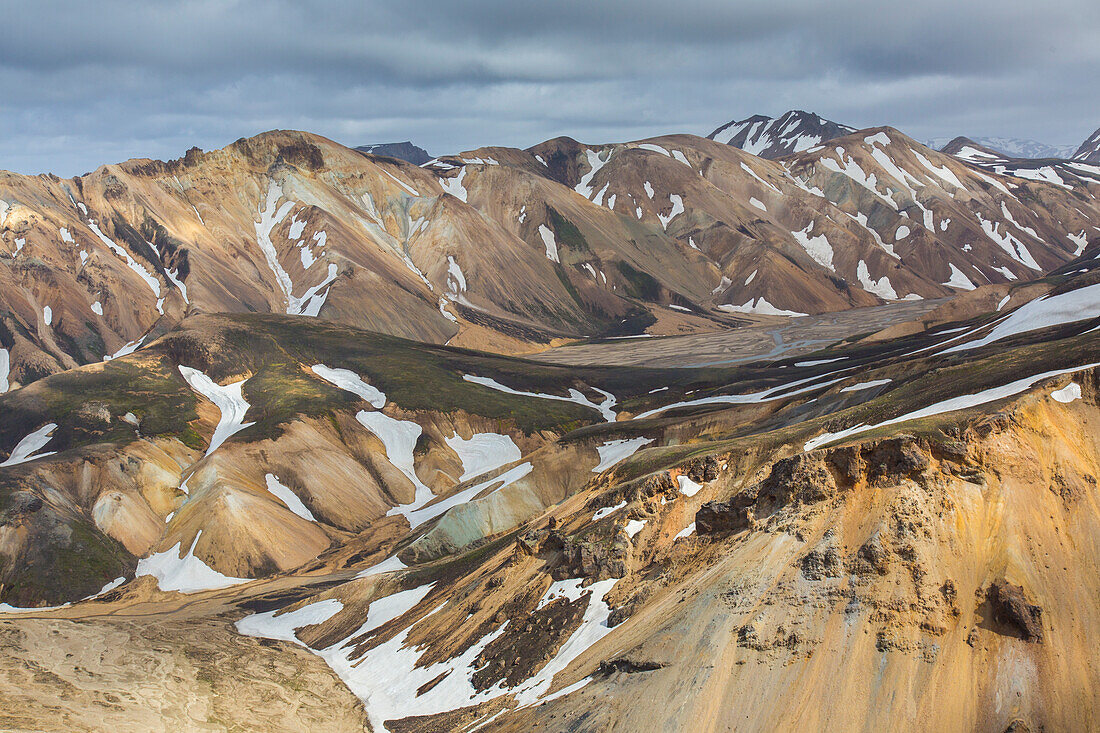  Colourful rhyolite mountains with snow residues at Blahnukur volcano in Landmannalaugar, Fjallabak National Park, Sudurland, Iceland 