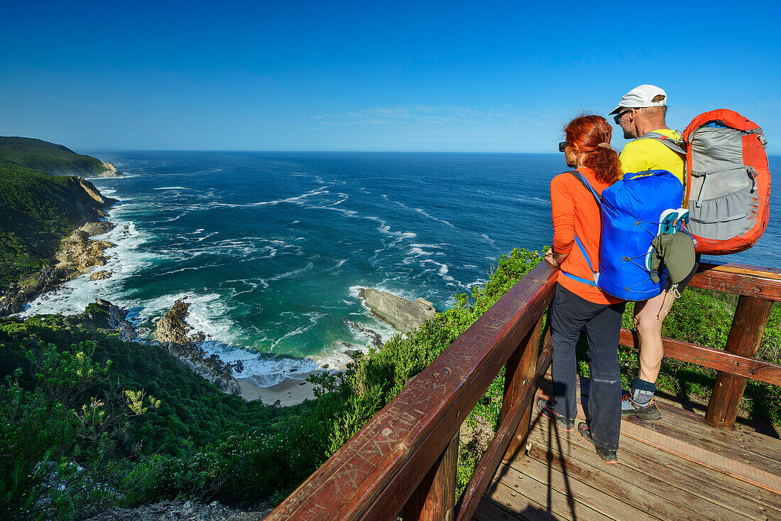  Man and woman hiking standing on viewing platform and looking at sandy beach Blou Baai, Otter Trail, Tsitsikamma Section, Garden Route National Park, Eastern Cape, South Africa 