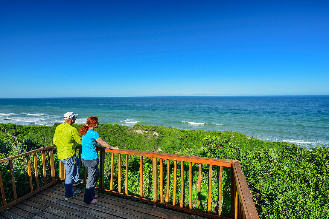  Man and woman hiking standing at viewing platform and looking out to sea, Alexandria Hiking Trail, Addo Elephant National Park, Eastern Cape, South Africa 