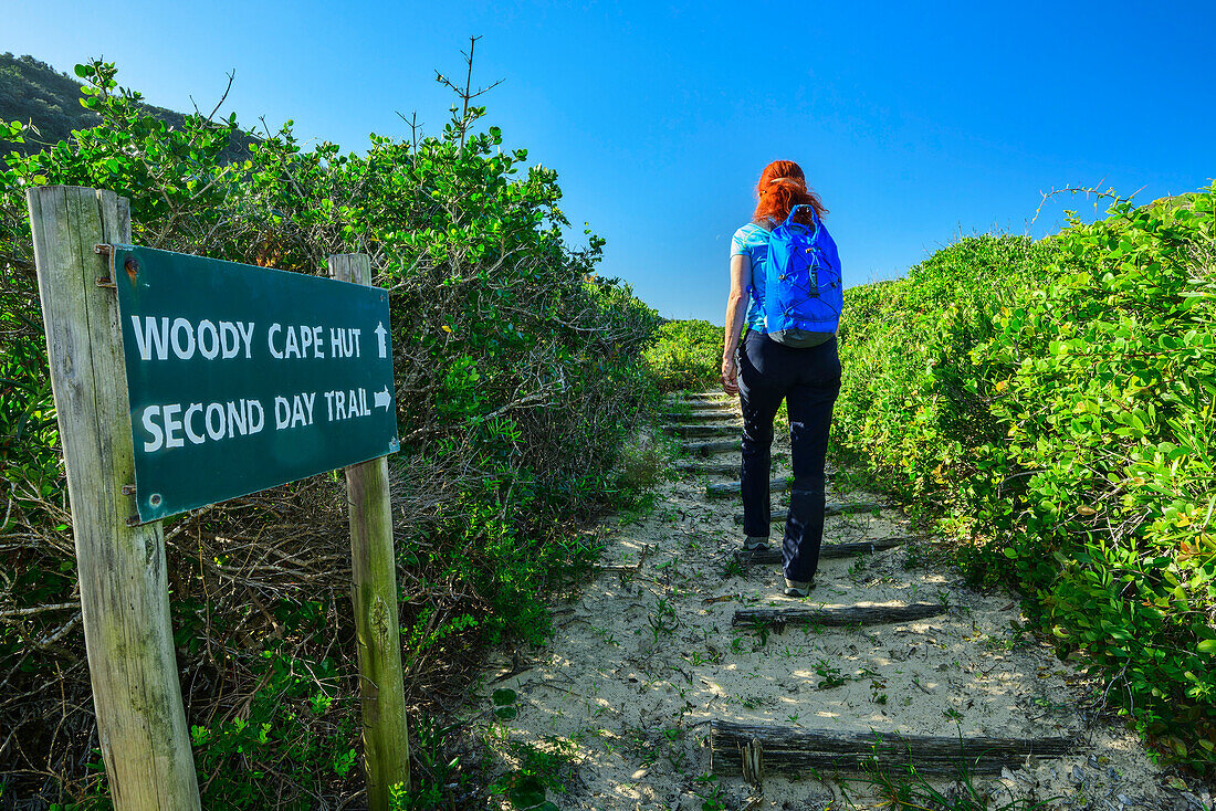 Frau wandert am Alexandria Hiking Trail, Wegweiser im Vordergrund, Alexandria Hiking Trail, Addo Elephant National Park, Eastern Cape, Südafrika